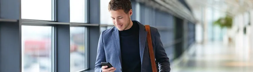 Jeune homme souriant qui consulte son téléphone