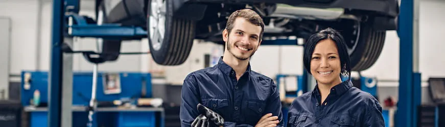 Une jeune femme et un jeune homme mécaniciens dans un garage auto
