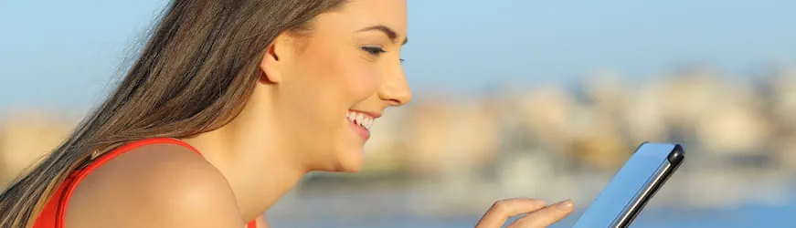 Une jeune femme découvre en souriant une offre d’emploi sur sa tablette.