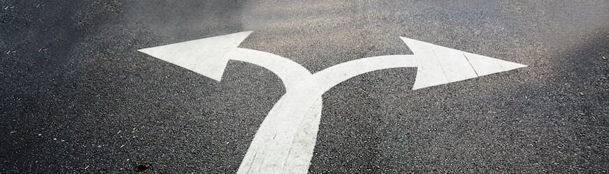 Une double flèche blanche sur la route, qui pointe vers la droite et la gauche