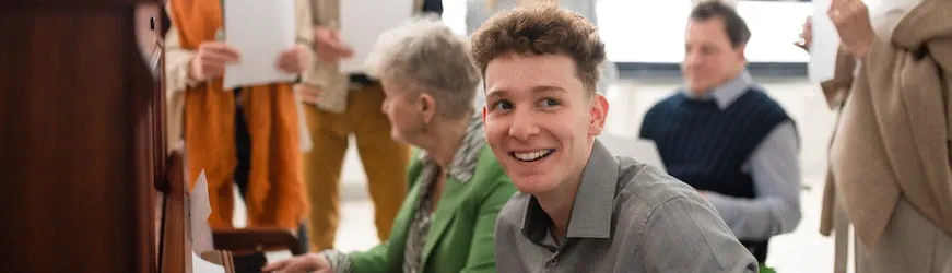 Un jeune homme réalisant son service civique au centre d’un groupe de personnes jouant de la musique