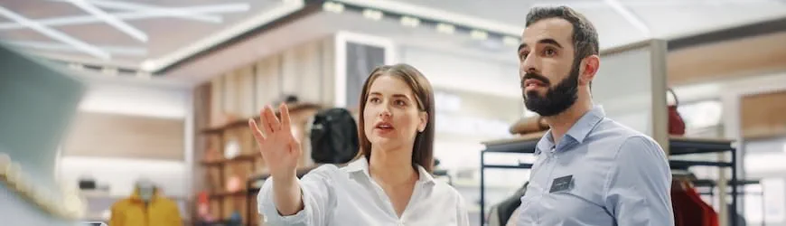 Une jeune salariée devenue manager dans un magasin donne une consigne à un collègue.