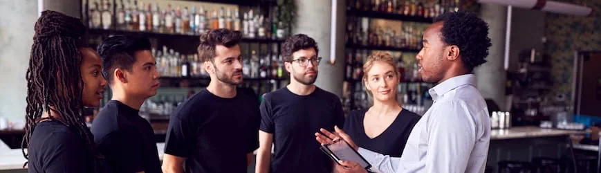 Un manager en train de gérer une équipe de serveurs d'un restaurant. 