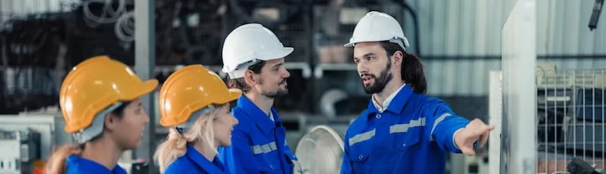 Un jeune manager dans un atelier industriel donne des consignes à son équipe. 