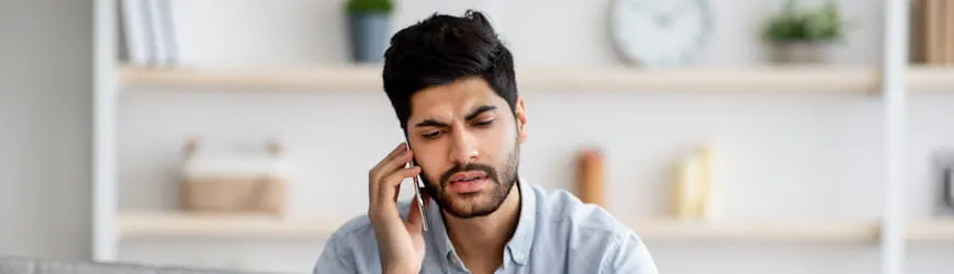 Un salarié au téléphone, en train de gérer des difficultés financières passagères avec sa banque.