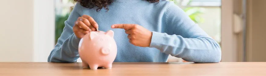 Une jeune intérimaire met de l’argent dans une tirelire, pour commencer à épargner.