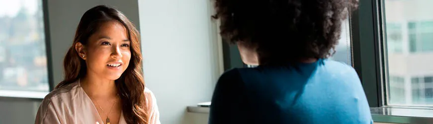 Deux femmes discutant en face à face dans un bureau.