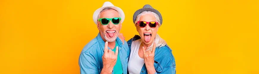 Un homme et une femme d’âge mûr sur un fond jaune vif. Ils portent des chapeaux et de lunette de soleil colorés. Ils tirent la langue de façon provocatrice en souriant et font un signe rock n roll de la main. Un homme et une femme d’âge mûr sur un fond jaune vif. Ils portent des chapeaux et de lunette de soleil colorés. Ils tirent la langue de façon provocatrice en souriant et font un signe rock n roll de la main.