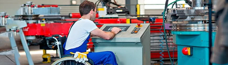 Un homme en fauteuil roulant effectue un réglage sur une machine industrielle