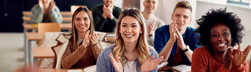 Jeunes filles et garçons en formation, assis dans une salle de classe. Ils sourient et applaudissent Jeunes filles et garçons en formation, assis dans une salle de classe. Ils sourient et applaudissent