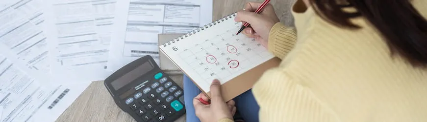 Une intérimaire contrôle ses jours travaillés sur un calendrier pour vérifier sa fiche de paie.
