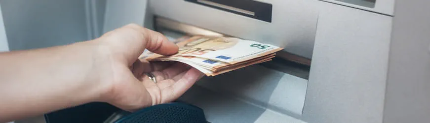 Un salarié retire une partie de son salaire à un distributeur automatique.