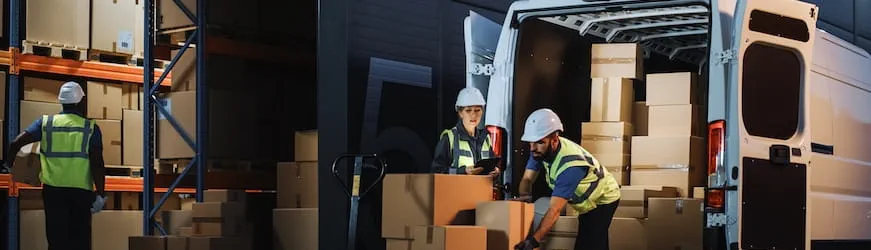 Une équipe qui décharge un camion devant un entrepôt logistique la nuit