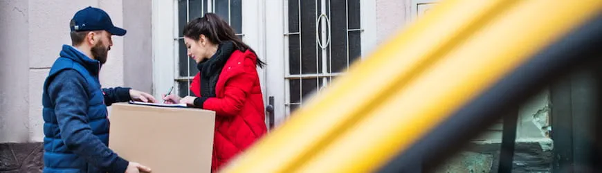 Un livreur qui donne un colis à une cliente dans la rue