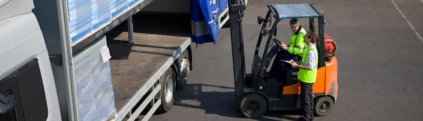 Un conducteur de chariot élévateur en train de charger une palette de marchandises dans un camion