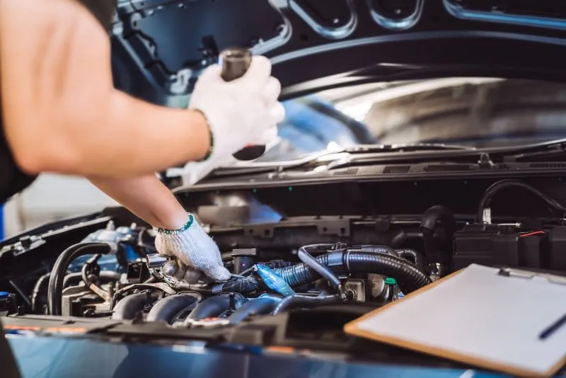 Mécanicien manipulant le moteur d’une voiture dans une usine automobile Mécanicien manipulant le moteur d’une voiture dans une usine automobile