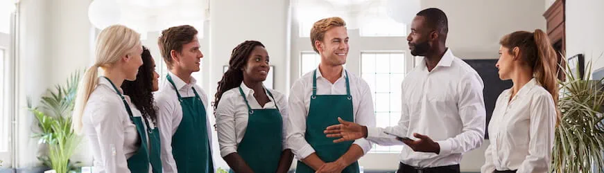 L’équipe de serveurs et de serveuses d’un restaurant, obligé·es de porter une chemise et un tablier au travail.