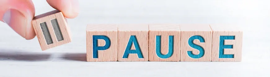 Une main pose des cubes de l’alphabet qui forment le mot Pause