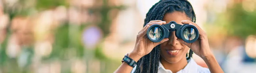 Une jeune femme qui regarde dans des jumelles, à la recherche d’un emploi alors qu’elle travaille déjà
