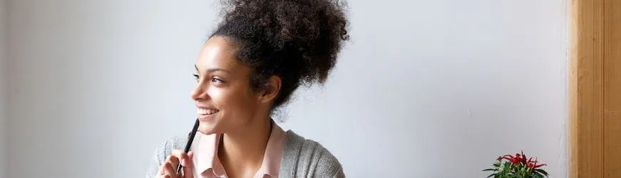 Une salariée, un stylo à la bouche, qui se demande comment demander un acompte sur salaire à son entreprise