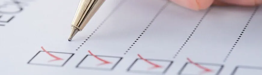 Une main qui tient un stylo et coche les cases d’une liste de points à aborder pendant un entretien d’évaluation annuel