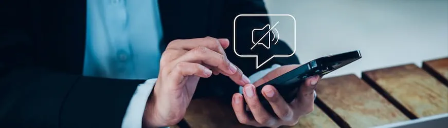 Les mains d’un salarié au travail qui met son téléphone personnel en mode silence