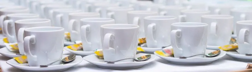 Plusieurs rangées de tasses à café positionnées sur le buffet d’un grand évènement