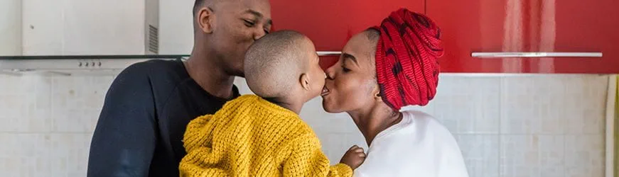 Jeune couple, heureux dans leur cuisine, avec leur bébé dans les bras. 