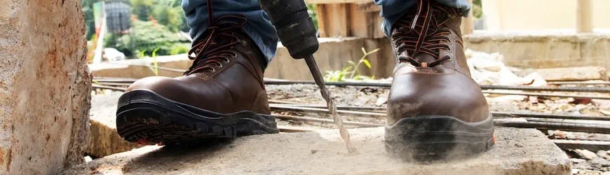 Gros plan sur les chaussures de sécurité d’un salarié travaillant dans le BTP.