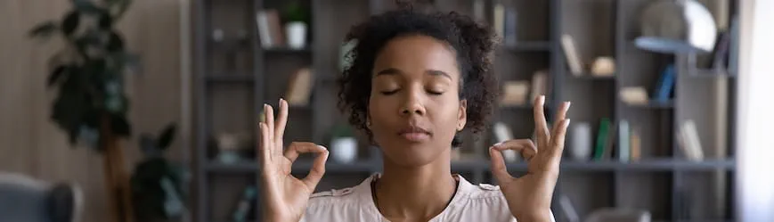 Une salariée se détend les yeux fermés en faisant les signes du zen avec les mains, avant de commencer se journée de travail au contact de la clientèle.