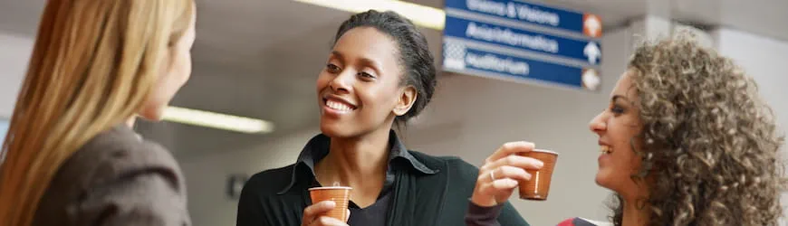 Trois collègues de travail qui discutent et rient ensemble pendant leur pause café.