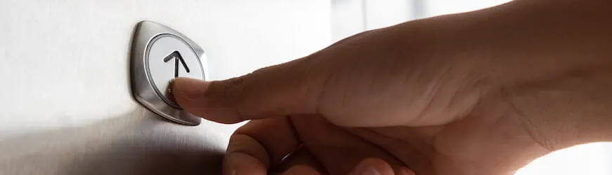 Un salarié qui appuie sur le bouton de l’ascenseur d’évolution professionnelle.