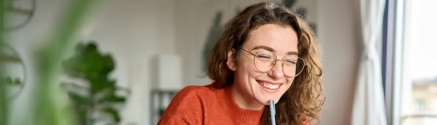 Une jeune femment découvre en souriant les avantages du CDI intérimaire sur son ordinateur.” 
