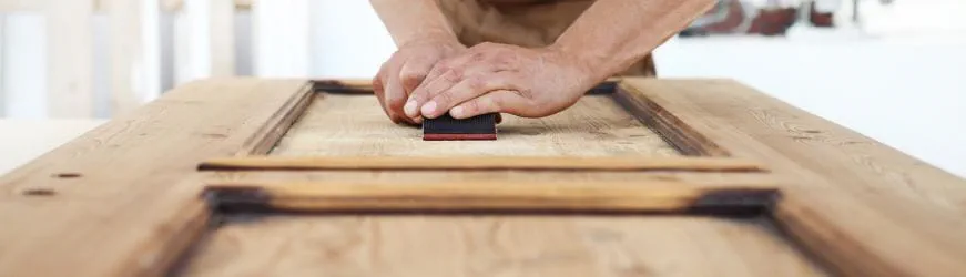 Un  professionnel de la menuiserie fabrique une porte en bois. 