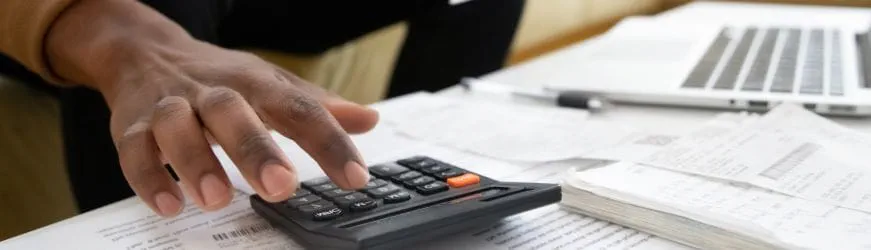 Les mains d’un intérimaire qui tape sur une calculatrice pour calculer le montant de la prime de fin de mission ou prime de précarité.