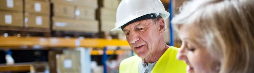Deux intérimaires seniors de plus de 50 ans travaillant dans un entrepôt logistique.