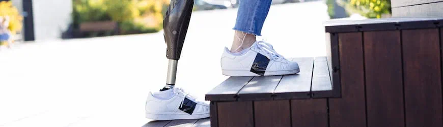 Une jeune salariée en situation de handicap, équipée d’une prothèse fémorale, monte un escalier pour se rendre à son travail.  