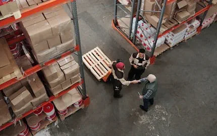 deux personnes dans un entrepot se serrent la main 