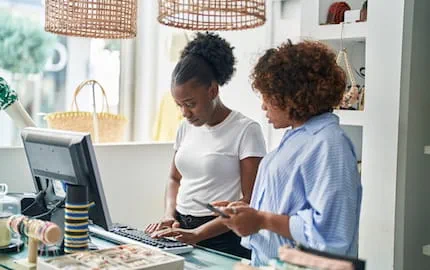Dans une boutique, une employeuse montre la caisse enregistreuse à son alternante qu'elle a recruté en cours d'année.
