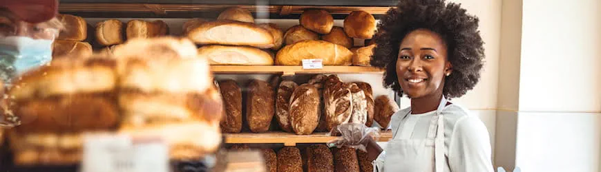 Une jeune femme souriante travaillant dans le rayon boulangerie d’une grande surface