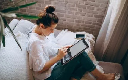 Une salariée qui télétravaille assise dans son canapé.