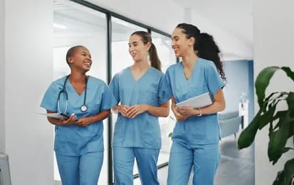Trois soignantes souriantes ayant des horaires flexibles terminant leur journée de travail Trois soignantes souriantes ayant des horaires flexibles terminant leur journée de travail