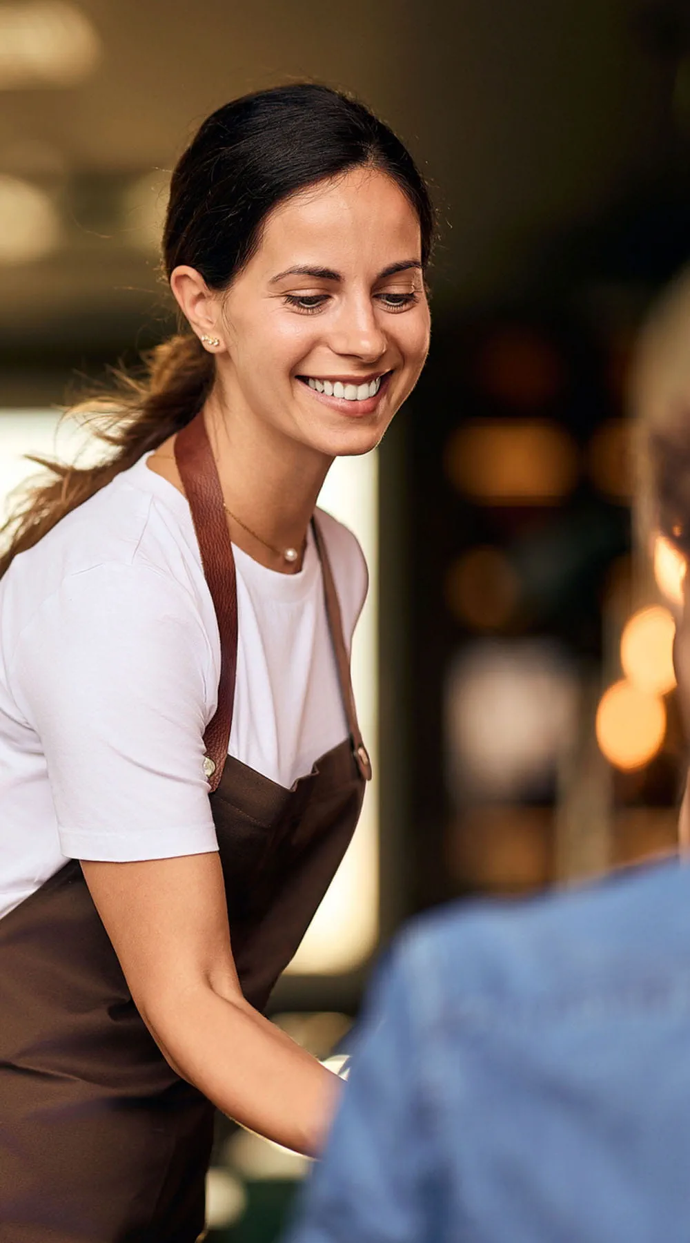 Camarera amable sonriendo mientras atiende a un cliente en un acogedor restaurante