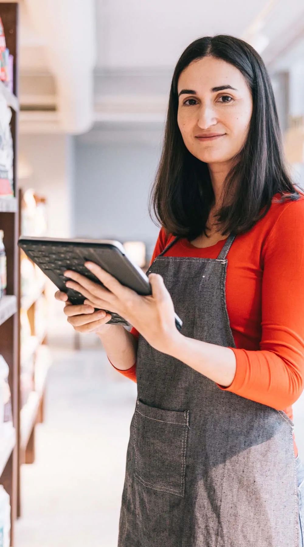 Tendera mira a cámara con una tablet en las manos