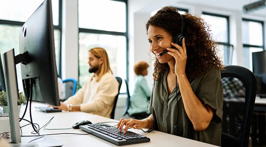 Mujer trabajando con ordenador en un call center de coworking Mujer trabajando con ordenador en un call center de coworking