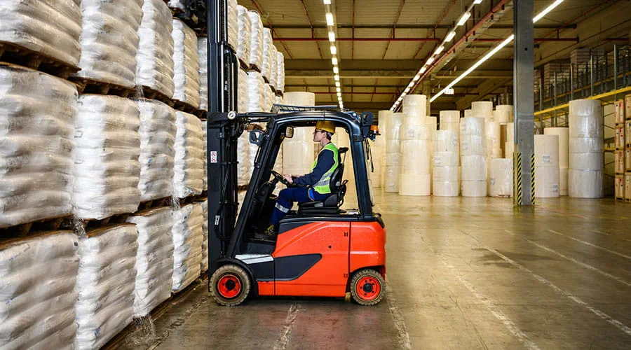 Trabajador cargando cajas con  carretilla elevadora en un almacén