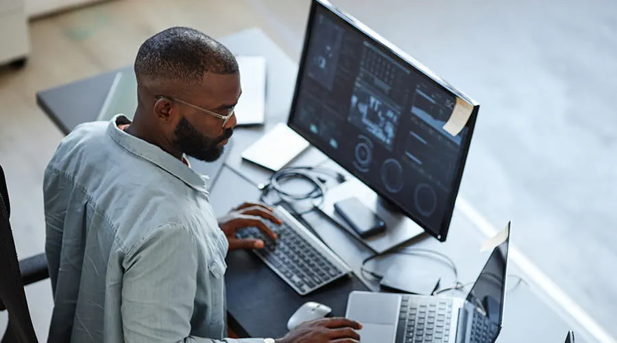 Hombre revisando dos monitores con datos