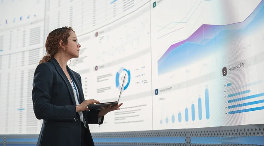 Mujer joven analizando datos en una gran pantalla