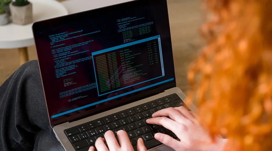 Mujer programando en un ordenador portátil en casa