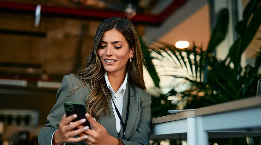 Mujer de negocios usando teléfono inteligente en la cafetería de la oficina moderna Mujer de negocios usando teléfono inteligente en la cafetería de la oficina moderna